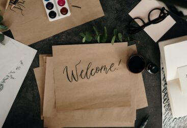 "Welcome!" written on brown paper, amid other items on a desk.